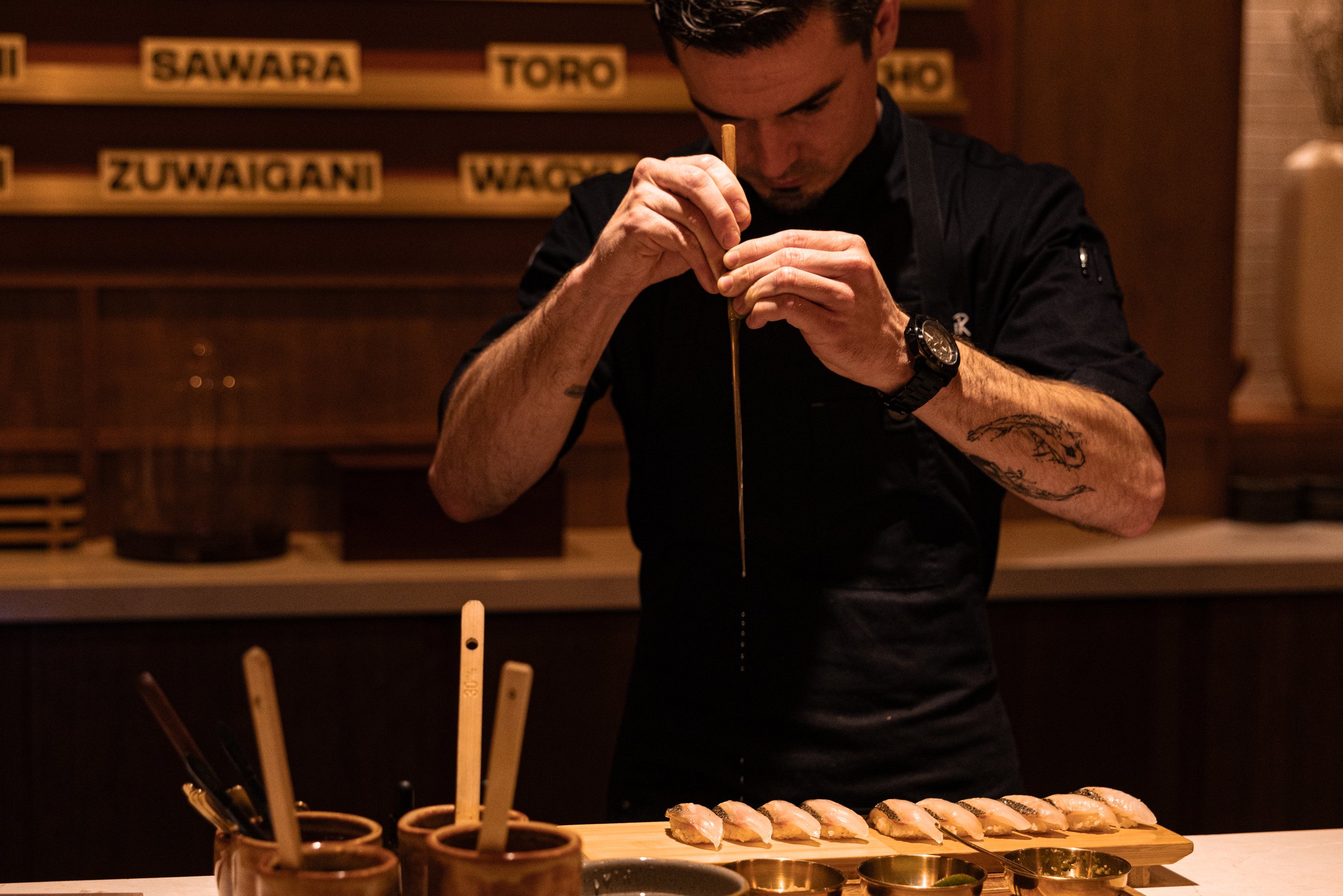 A chef finishing nigiri at the counter