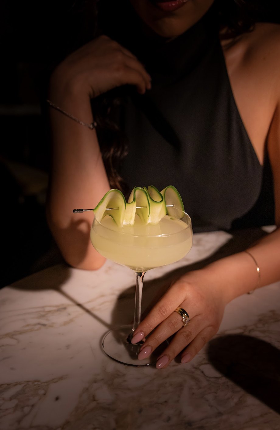 A cocktail with cucumber garnish